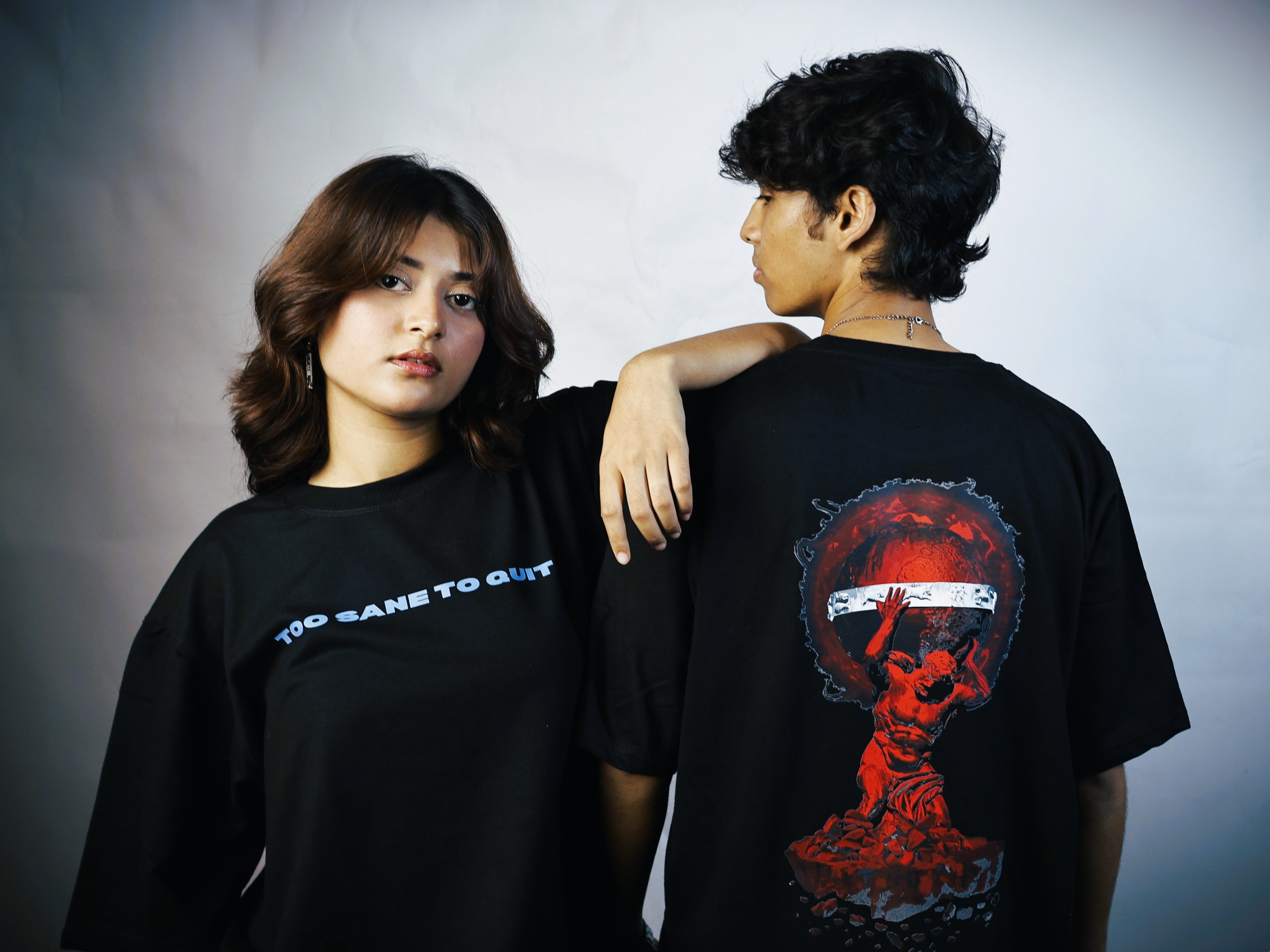 Two people wearing black t-shirts, one with a graphic design on the back.